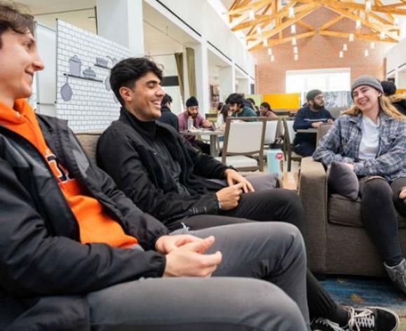 three students sit on couches in the DeRosa University Center